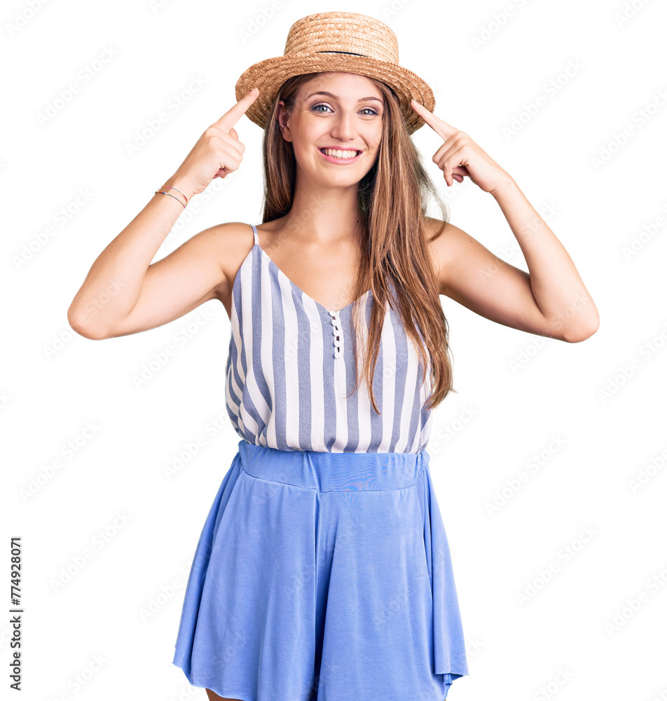 Young beautiful blonde woman wearing summer hat smiling pointing to head with both hands finger, great idea or thought, good memory Young beautiful blonde woman wearing summer hat smiling pointing to head with both hands finger, great idea or thought, good memory