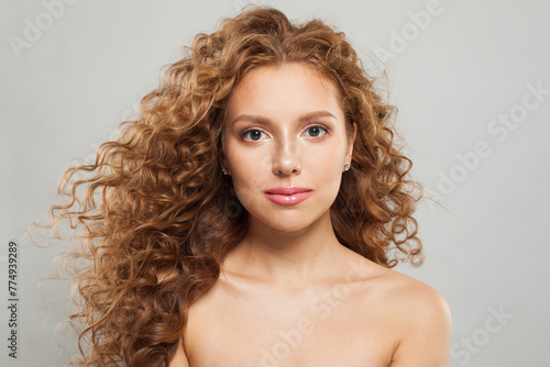 Attractive fashion model with frizzy hair, natural makeup and healthy clean skin posing on white background. Skincare, haircare and cosmetology concept
