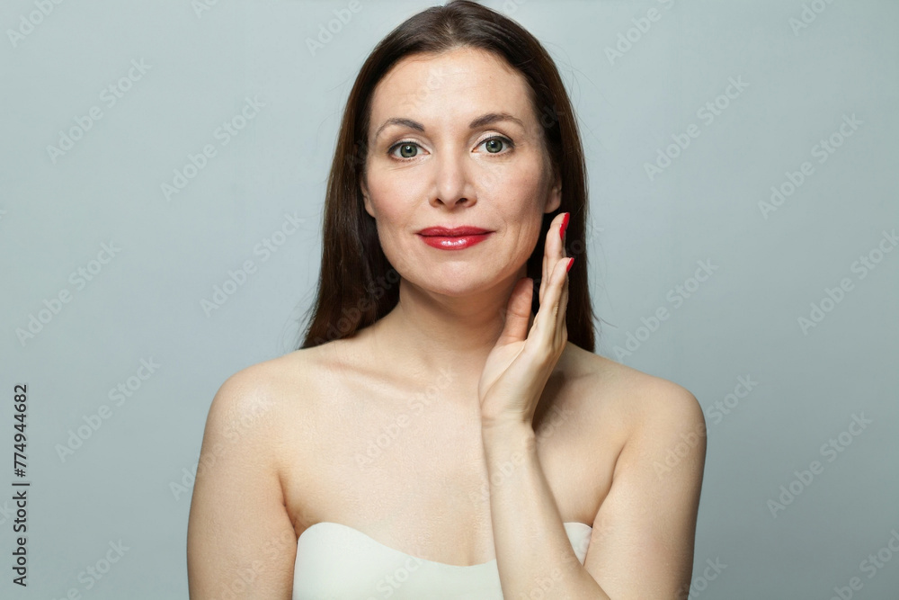 Brunette senior older woman touching her skin. Beautiful portrait mid adult 50s aged model. Facial treatment, antiage, lifting and cosmetology concept Brunette senior older woman touching her skin. Beautiful portrait mid adult 50s aged model. Facial treatment, antiage, lifting and cosmetology concept
