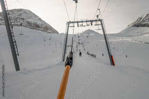 Lifting on the ski drag lift rope over sunlight near mountain peak