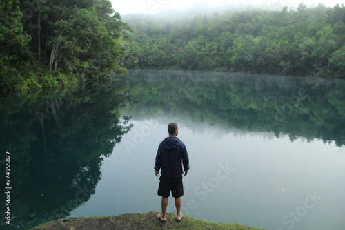 homem na beira de lagoa azul em serra do navio, amapá, em amanhecer com neblina photo