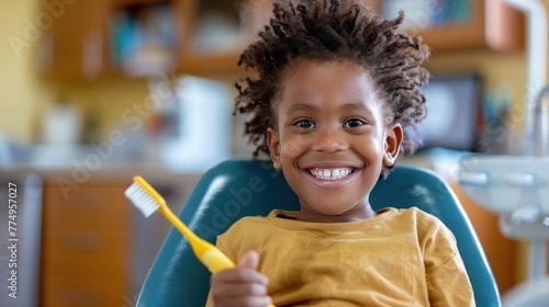 An image of a smiling child sitting in a dentist's chair, holding a toothbrush and eagerly waiting for their dental check photo