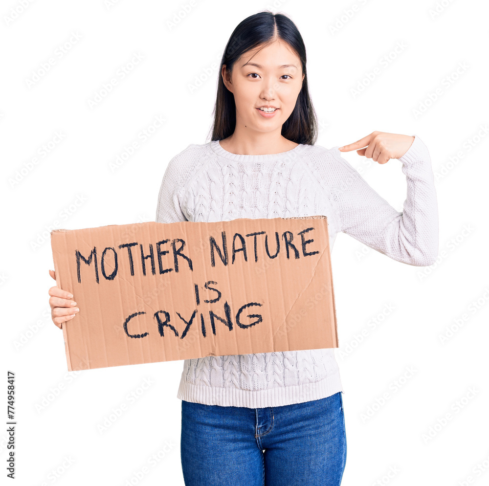 Young beautiful chinese woman holding mother nature is crying cardboard banner pointing finger to one self smiling happy and proud Young beautiful chinese woman holding mother nature is crying cardboard banner pointing finger to one self smiling happy and proud