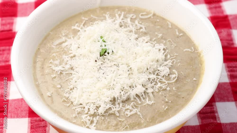 Creamy mushroom soup in a bowl. Sprinkle grated cheese over the soup. Garnish with slices of sautéed mushrooms Creamy mushroom soup in a bowl. Sprinkle grated cheese over the soup. Garnish with slices of sautéed mushrooms