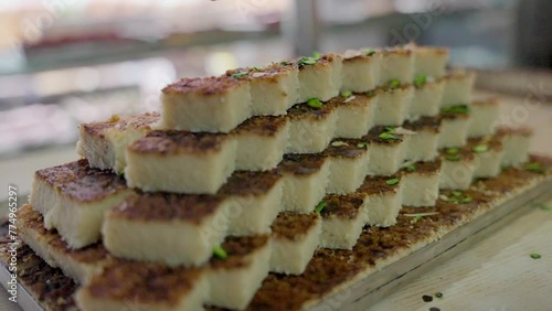 Closeup shot of a person pouring pistachios on a pile of Indian mithai sweets photo