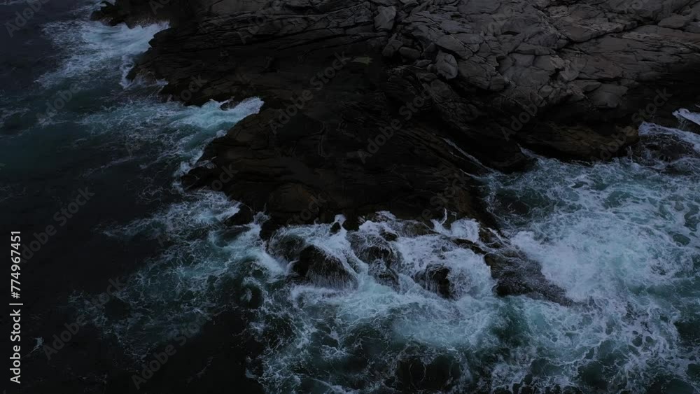 Dramatic aerial view of the foamy waves splashing on a huge rock Dramatic aerial view of the foamy waves splashing on a huge rock