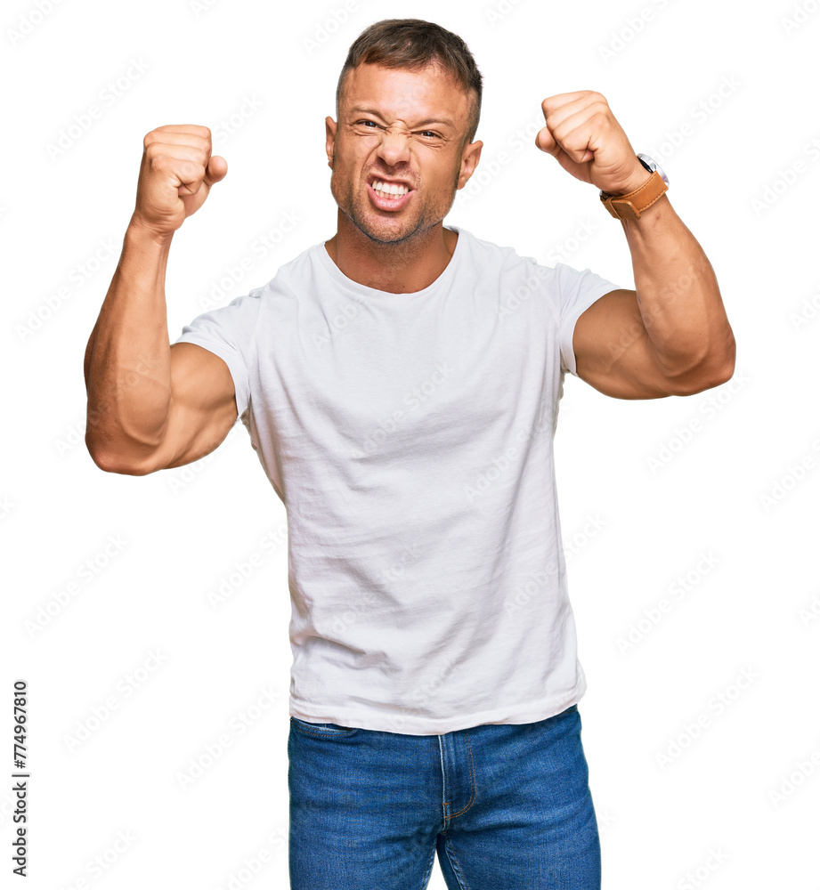 Handsome muscle man wearing casual white tshirt angry and mad raising fists frustrated and furious while shouting with anger. rage and aggressive concept. Handsome muscle man wearing casual white tshirt angry and mad raising fists frustrated and furious while shouting with anger. rage and aggressive concept.