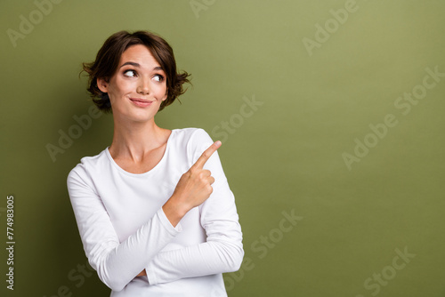 Portrait of charming girl direct finger empty space announcement sale offer shop store mall isolated khaki green color background