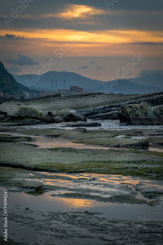 Sunset time at the coastline of Badouzi, sunlight shines on the water with gorgeous rocks and seaweed by the side, in Keelung city, Taiwan. photo