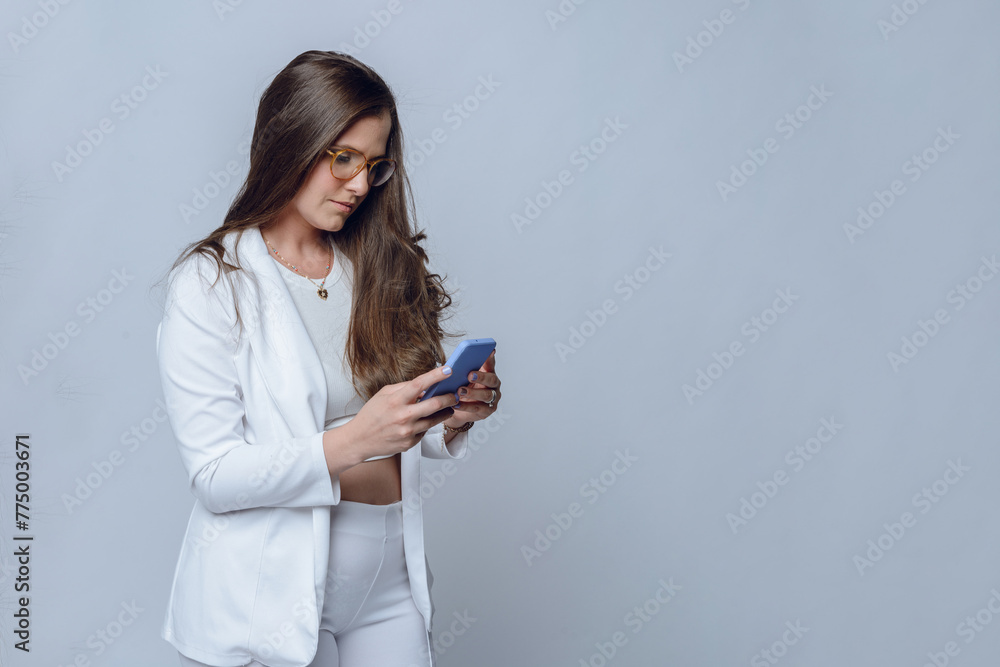 young latin businesswoman, with glasses and long hair, using and watching cell phone, copy space. young latin businesswoman, with glasses and long hair, using and watching cell phone, copy space.