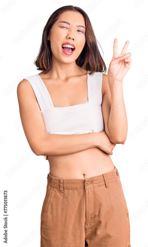 Young beautiful chinese girl wearing casual clothes smiling with happy face winking at the camera doing victory sign. number two. Young beautiful chinese girl wearing casual clothes smiling with happy face winking at the camera doing victory sign. number two.