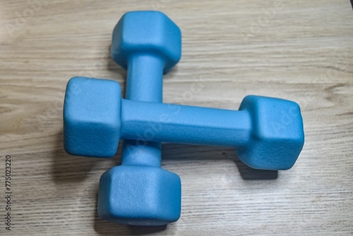 Closeup of a pair of blue dumbbells on a wooden background