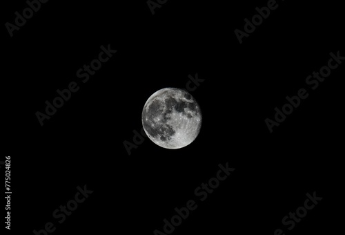 Scenic closeup of the full moon in the black night sky, cool for background