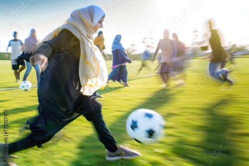 Blurred dynamic shot of a covered muslim woman or girl playing soccer with a group of friends, dribbling the ball and showing her agility on the field.