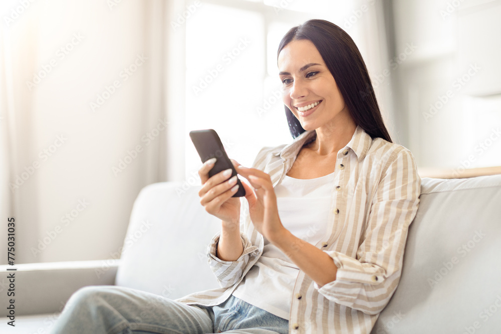 Casual woman browsing on smartphone at home Casual woman browsing on smartphone at home