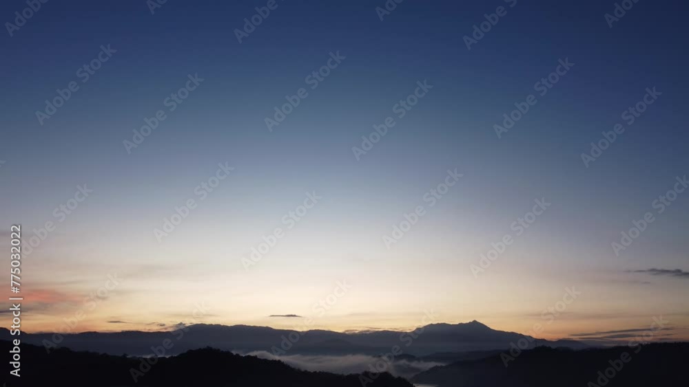 Descending drone view of a morning sunrise overlooking shadowed lands Descending drone view of a morning sunrise overlooking shadowed lands