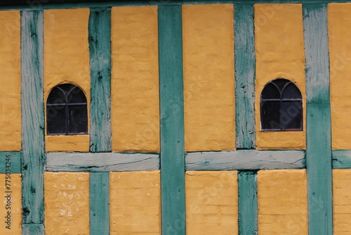 Yellow wall with windows and wooden blue lines.