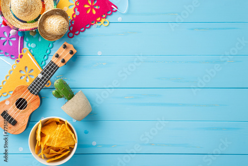 Mexican Fiesta theme. Overhead shot of festive elements: sombreros, guitar, cactus, flag decor, and nachos on rustic blue backdrop. Perfect for promotions or invitations