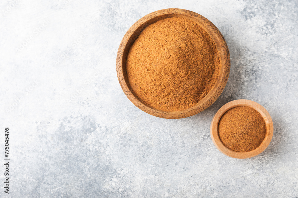 Cinnamon powder in a bowl on a textured wooden background. Spicy spice for baking, desserts and drinks. Fragrant ground cinnamon. Cinnamon stick. Place for text. Copy space. Cinnamon powder in a bowl on a textured wooden background. Spicy spice for baking, desserts and drinks. Fragrant ground cinnamon. Cinnamon stick. Place for text. Copy space.