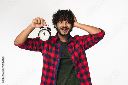 Panicking young Indian man holding clock hurrying up isolated over white background. Hindi boy having deadline, showing 5 minutes till the end, time is up concept photo