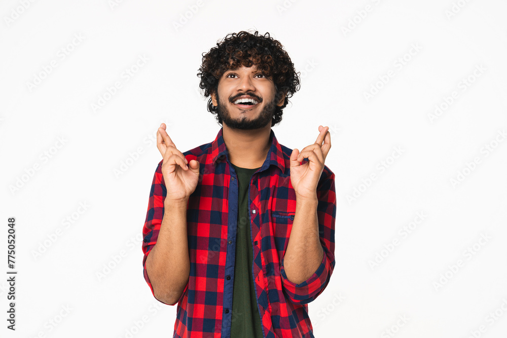 Happy young Indian man in casual clothes making wish with fingers crossed isolated over white background. Hindi boy praying, expecting good changes, asking God Happy young Indian man in casual clothes making wish with fingers crossed isolated over white background. Hindi boy praying, expecting good changes, asking God