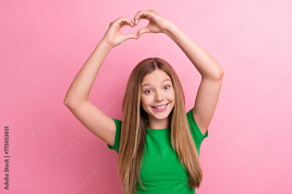 Photo portrait of pretty teenager girl raise hands show heart gesture dressed stylish green outfit isolated on pink color background Photo portrait of pretty teenager girl raise hands show heart gesture dressed stylish green outfit isolated on pink color background