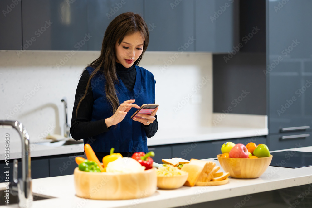 Happy woman relaxing at home - young Asian woman Relaxed and taking online courses for preparation dinner with organic fresh meal.