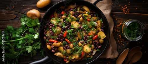 A cooking pan filled with beans and potatoes placed next to a bunch of fresh parsley, perfect for a delicious meal preparation