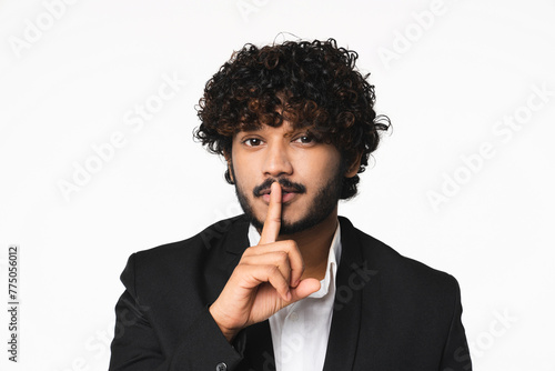 Attractive young Hindu businessman with finger on lips isolated over white background. Handsome Indian manager CEO boss having secret , showing silent gesture