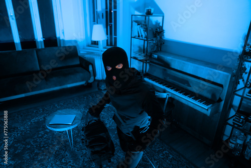 Burglar with full backpack examining living room
