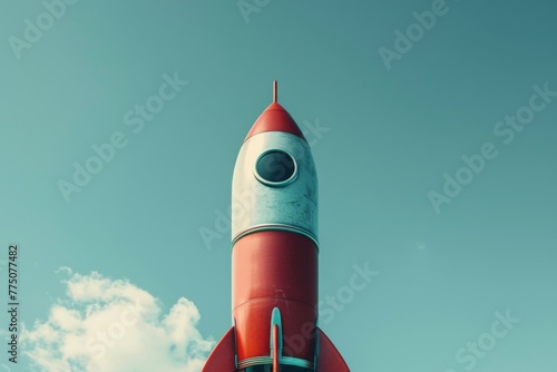 Vintage red toy rocket soaring into a clear blue sky, representing creativity and adventure
