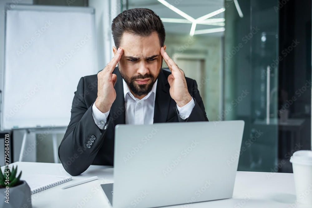 Tired exhausted man, office worker, manager sitting at his desk, tired of working in a laptop, overworked, having a headache, closed his eyes, need rest and break