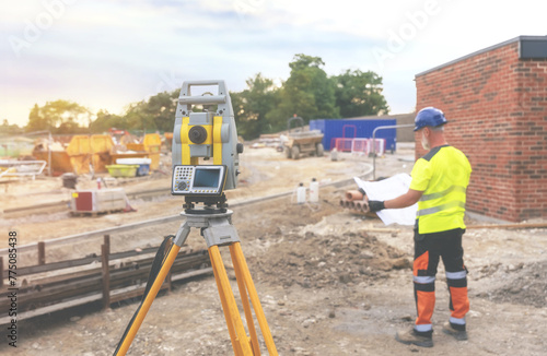 A man site engineer surveyor working with theodolite total station EDM equipment on a building construction site outdoors toned image
