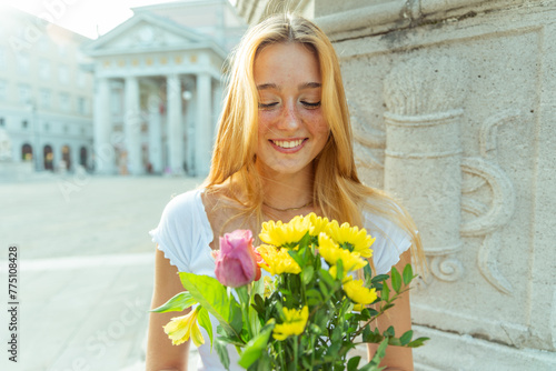 A happy girl looks at a bouquet of flowers she has just received as a gift, romantic gesture
