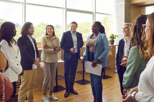 Group of business people chatting after meeting. Diverse company employees listening african americam woman colleague with a report in conference room standing in a circle in modern office.