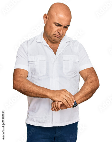 Mature middle east man with mustache wearing casual white shirt checking the time on wrist watch, relaxed and confident