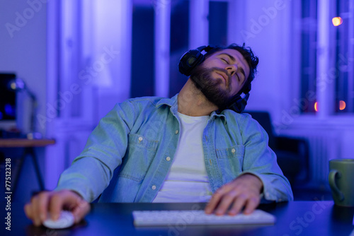 Exhausted man asleep at computer desk at home photo