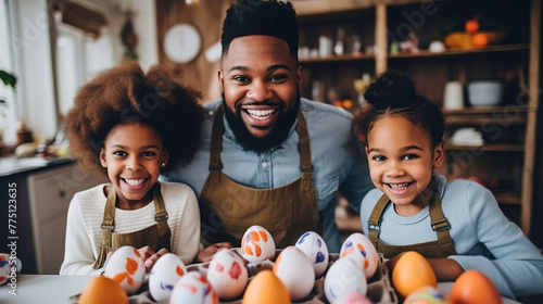 A cheerful dad is working with his children on decorating Easter eggs in his creative studio. photo