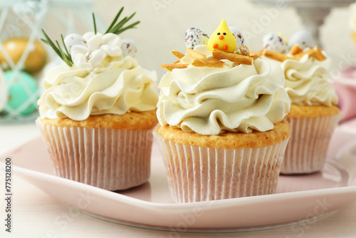 Tasty Easter cupcakes with vanilla cream on light wooden table