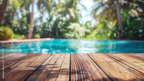 Abstract background with a wooden table top and a blurred swimming pool in the summer garden. A colorful wood floor for product display, a tropical beach, vacation concept.