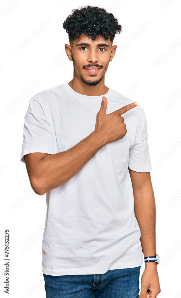 Young arab man wearing casual white t shirt cheerful with a smile on face pointing with hand and finger up to the side with happy and natural expression Young arab man wearing casual white t shirt cheerful with a smile on face pointing with hand and finger up to the side with happy and natural expression