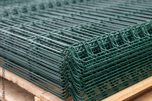 PVC Coated Curvy Welded Fence on warehouse. Building materials. Green sections of wire mesh for fencing on racks photo