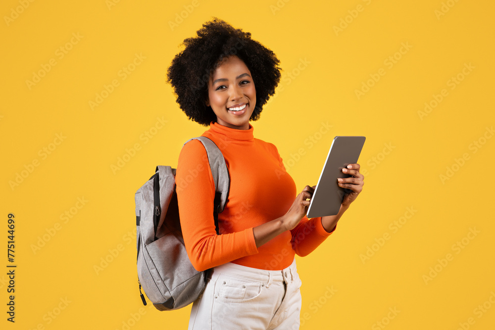 Confident African American woman with curly hair smiling and holding a digital tablet Confident African American woman with curly hair smiling and holding a digital tablet