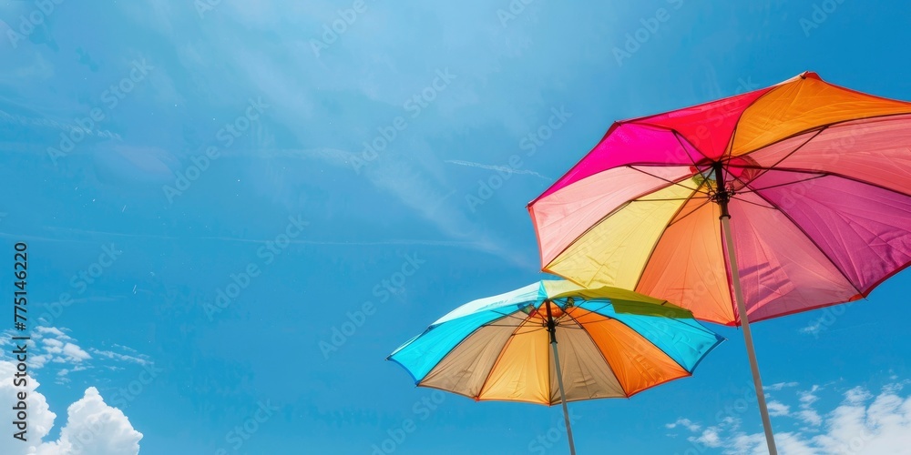 two colorful beach umbrellas against the blue sky, summer background