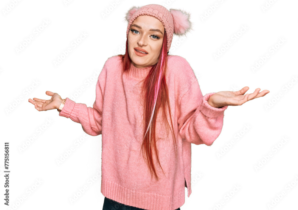 Young caucasian woman wearing casual clothes and wool cap clueless and confused expression with arms and hands raised. doubt concept. Young caucasian woman wearing casual clothes and wool cap clueless and confused expression with arms and hands raised. doubt concept.