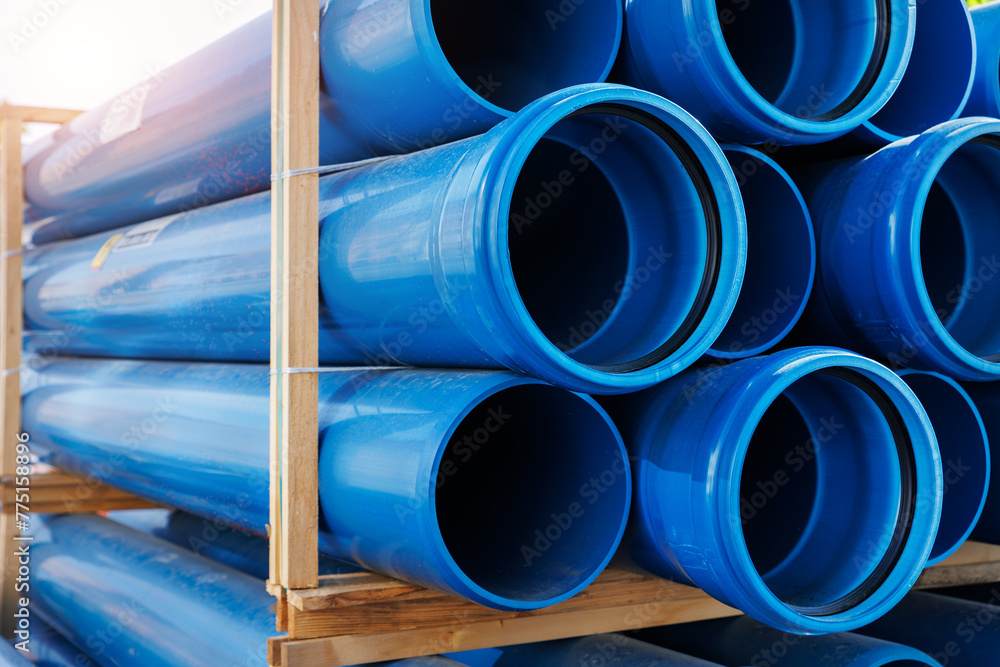 Close-up blue PVC plumbing pipes stacked wooden pallets replacement at german city street infrastructure construction site. Town development building industrial background Close-up blue PVC plumbing pipes stacked wooden pallets replacement at german city street infrastructure construction site. Town development building industrial background