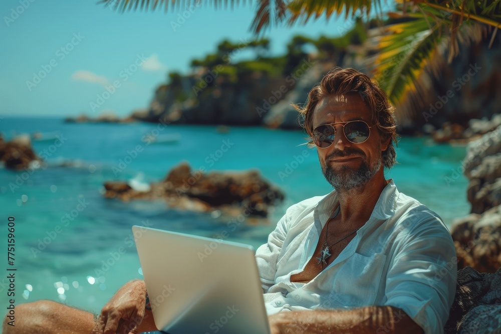 Tranquil beach scene: Man in white shirt working on laptop, sunny day, birch sea