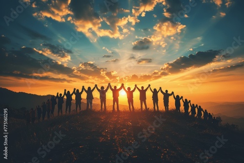 Silhouettes of people holding hands and celebrating success with arms raised against the sky at sunset, representing community support for individuals in need. photo