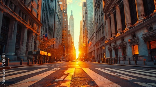 A city street with a large building in the background. The sun is setting and the sky is orange