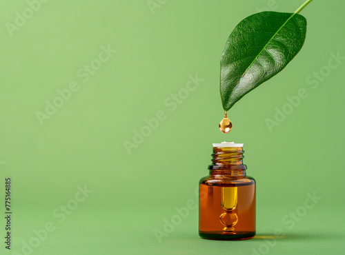 Jar with oil on top of green leaf with drop on green background